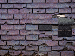 Cracked and curled shingles on a damaged roof in need of repair.